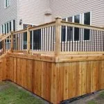 a newly constructed wooden deck with railing and stairs, crafted by stittsville deck builder, is attached to a residential house.