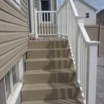 exterior staircase of a residential building with beige vinyl siding, expertly crafted by stittsville deck builder, featuring white railings and a pair of shoes left on one of the steps under a clear