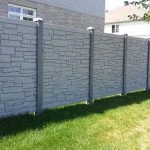 a stone fences with a tree in front of it.