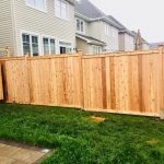 A new cedar fence installed between two residential properties, featuring a circular cut-out detail.
