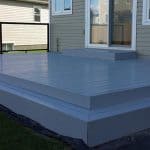 A grey deck with a black railing constructed by experienced deck builders in Ottawa.