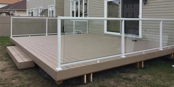 newly constructed wooden decking solutions with a white railing surrounding it.