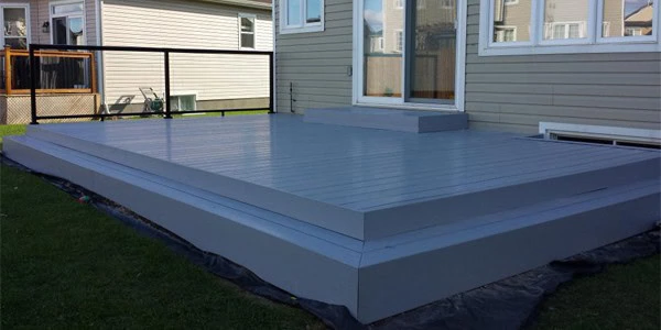 low-profile, gray pvc decking in a backyard with a railing and neighboring houses in the background.