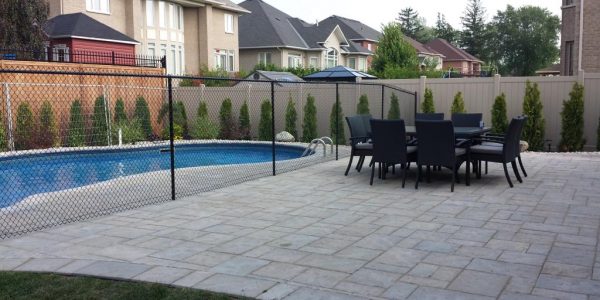 A patio with a pool, a table and chairs, and fences.