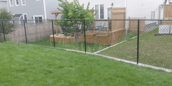 a backyard featuring a black chain link fence, chain link fence installation, chain-link fencing